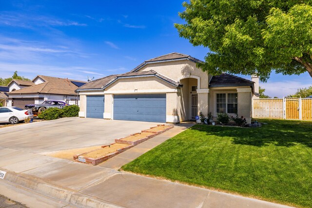mediterranean / spanish home featuring a front lawn, fence, stucco siding, concrete driveway, and an attached garage
