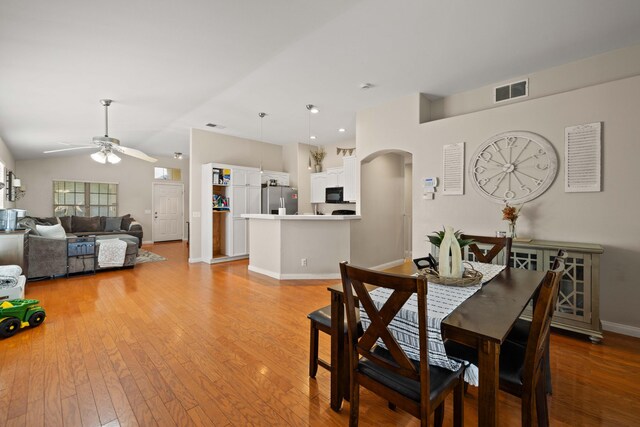 dining room featuring arched walkways, a ceiling fan, light wood-type flooring, and visible vents