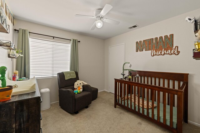 bedroom with visible vents, a ceiling fan, carpet, and a nursery area