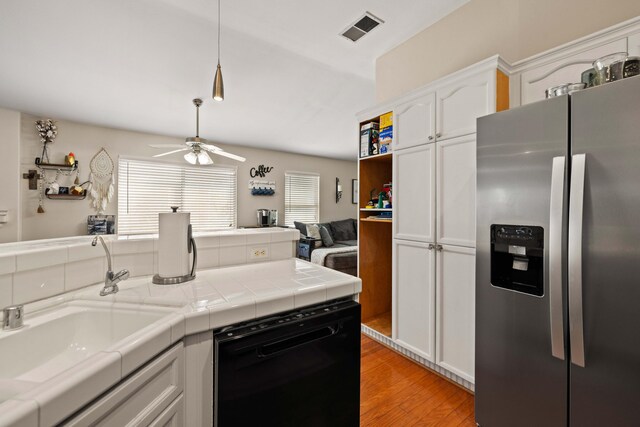 kitchen featuring visible vents, stainless steel fridge with ice dispenser, white cabinets, light wood finished floors, and black dishwasher