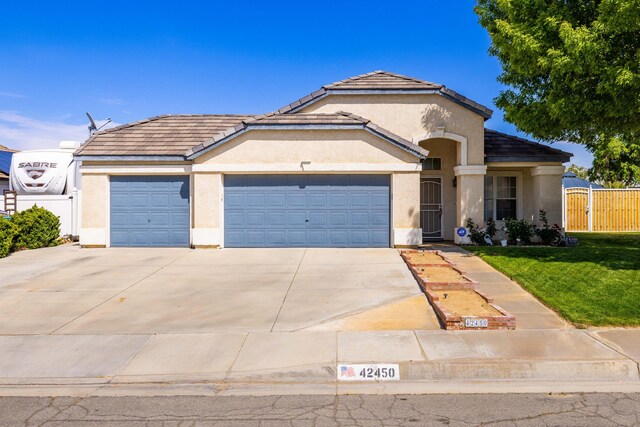 mediterranean / spanish house with fence, an attached garage, a front lawn, stucco siding, and concrete driveway