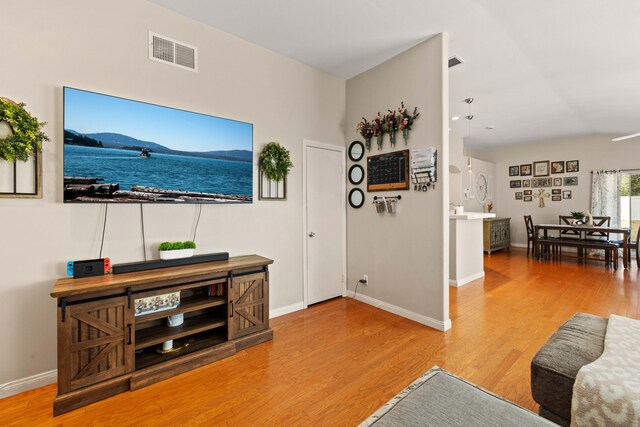 living area with baseboards, light wood-style flooring, and visible vents