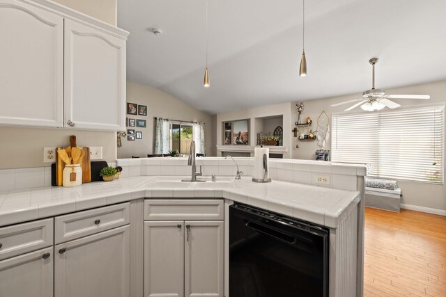 kitchen with a ceiling fan, dishwasher, a sink, a peninsula, and lofted ceiling