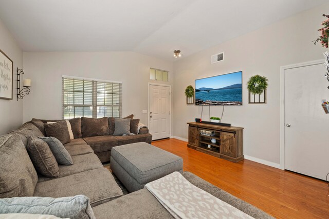 living area featuring baseboards, lofted ceiling, wood finished floors, and visible vents