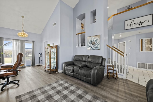 living room with high vaulted ceiling, wood-type flooring, and an inviting chandelier