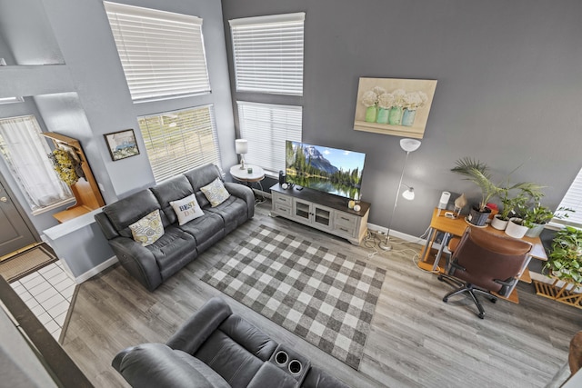 living room with light wood-type flooring and a towering ceiling