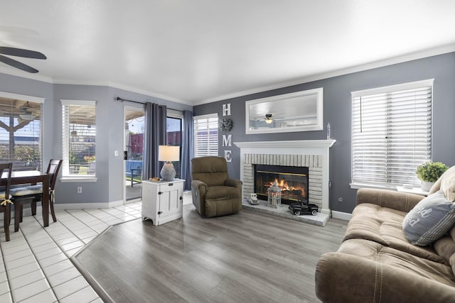 living room with a wealth of natural light, a fireplace, and ceiling fan