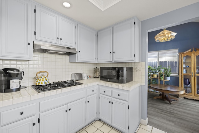 kitchen featuring white cabinetry, stainless steel gas cooktop, and tile counters