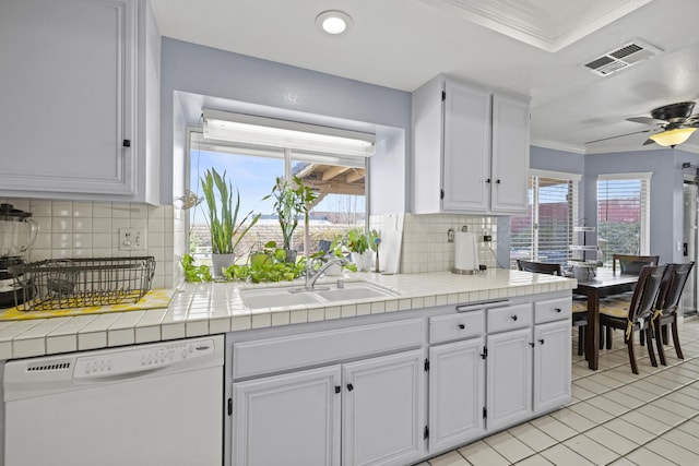 kitchen with white dishwasher, white cabinets, sink, and tile countertops