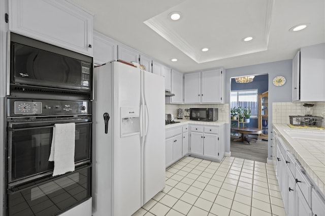 kitchen with white cabinetry, a raised ceiling, tasteful backsplash, and black appliances