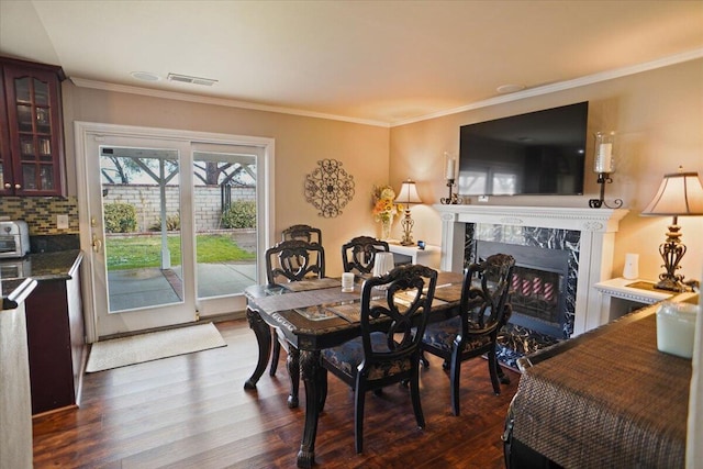 dining area featuring crown molding, a high end fireplace, and dark hardwood / wood-style floors