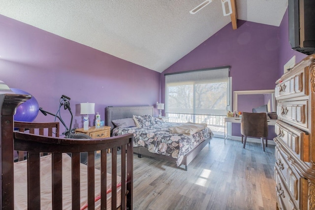 bedroom featuring vaulted ceiling with beams, ceiling fan, a textured ceiling, and light wood-type flooring