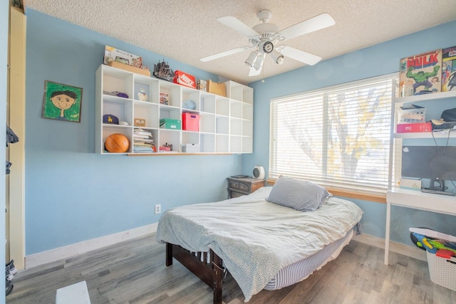 bedroom with hardwood / wood-style floors, ceiling fan, and a textured ceiling