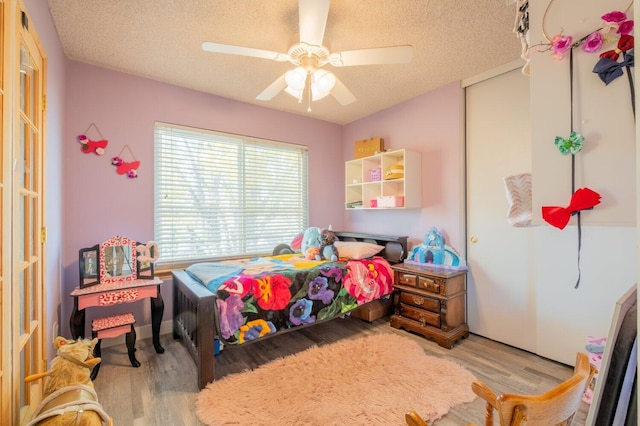 bedroom with ceiling fan, light hardwood / wood-style flooring, and a textured ceiling