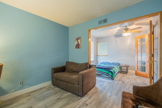 bedroom featuring french doors, a textured ceiling, light hardwood / wood-style floors, and ceiling fan