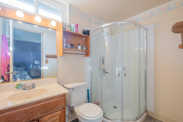 bathroom with a shower with door, vanity, and toilet