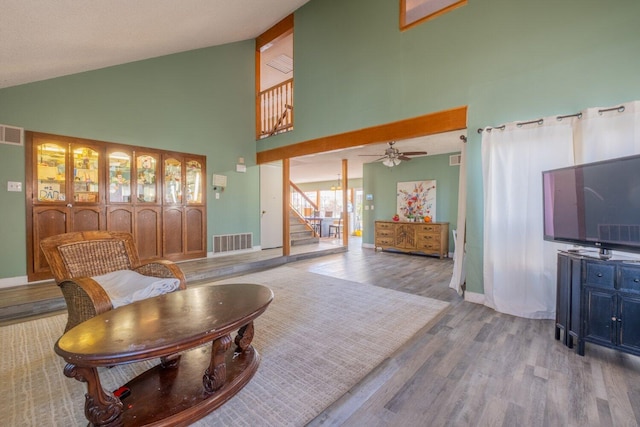 living room with light wood-type flooring, high vaulted ceiling, and ceiling fan