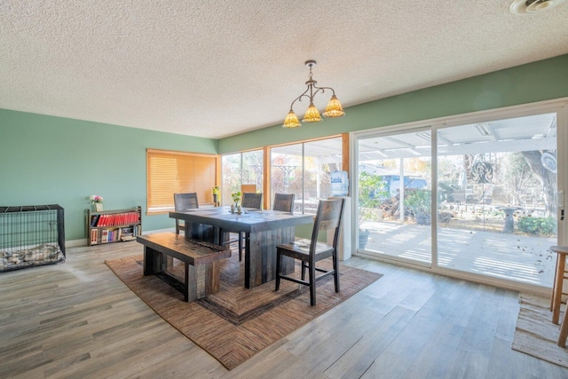 dining space featuring a textured ceiling, hardwood / wood-style flooring, and an inviting chandelier