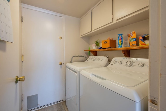 washroom with cabinets, separate washer and dryer, and wood-type flooring