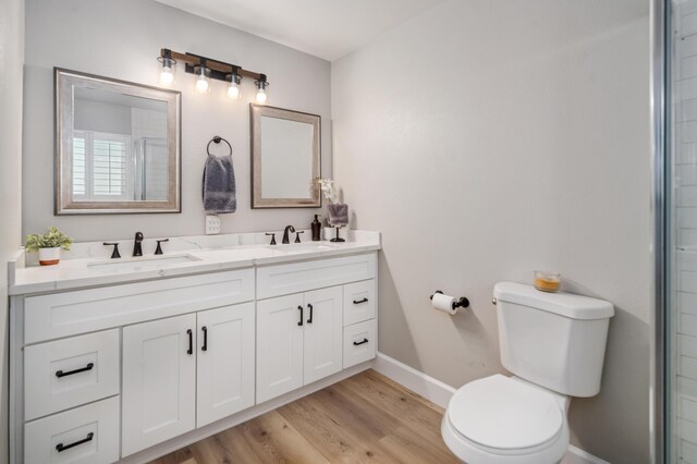 bathroom featuring hardwood / wood-style floors, vanity, toilet, and a shower with shower door