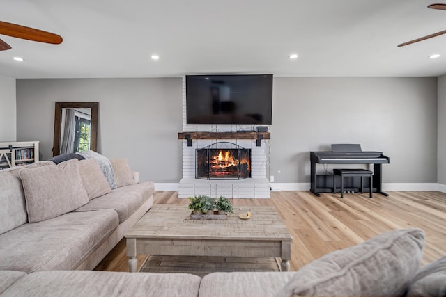 living room featuring a fireplace, hardwood / wood-style flooring, and ceiling fan