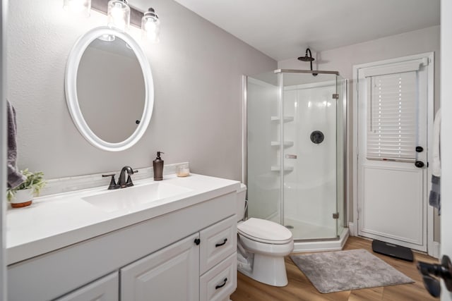 bathroom with toilet, vanity, an enclosed shower, and hardwood / wood-style flooring