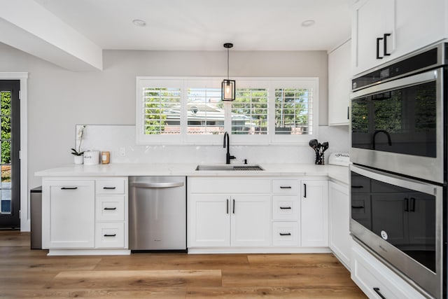 kitchen featuring white cabinetry, sink, stainless steel appliances, backsplash, and light wood-type flooring