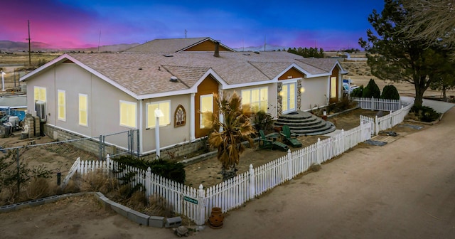 view of front of house featuring a shingled roof and a fenced front yard