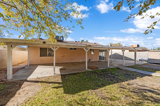 rear view of property featuring cooling unit, a yard, and a patio