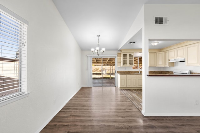 kitchen with hanging light fixtures, cream cabinetry, wood-type flooring, a chandelier, and lofted ceiling