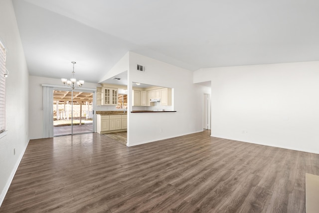 unfurnished living room featuring a notable chandelier, dark hardwood / wood-style floors, and vaulted ceiling