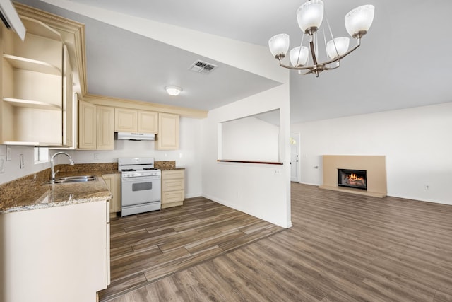 kitchen with an inviting chandelier, sink, light stone countertops, decorative light fixtures, and white range oven