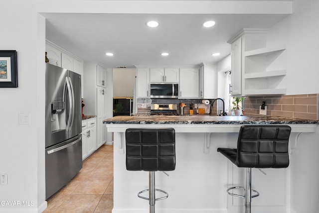 2512 Mildwood Ct, Lancaster, CA 93536 - kitchen featuring appliances with stainless steel finishes, a peninsula, white cabinetry, decorative backsplash, and recessed lighting