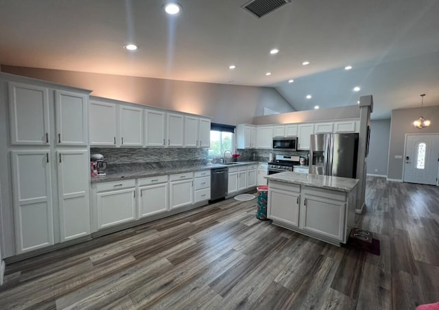 kitchen with appliances with stainless steel finishes, backsplash, white cabinetry, and lofted ceiling