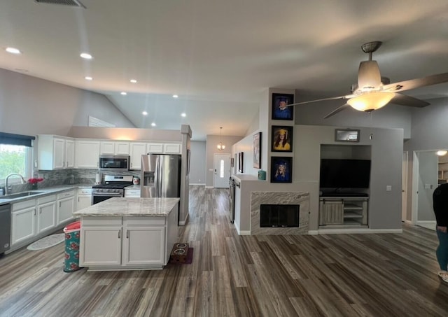 kitchen featuring stainless steel appliances, a kitchen island, lofted ceiling, decorative backsplash, and white cabinets