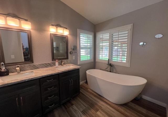 bathroom with a washtub, vanity, lofted ceiling, and hardwood / wood-style flooring