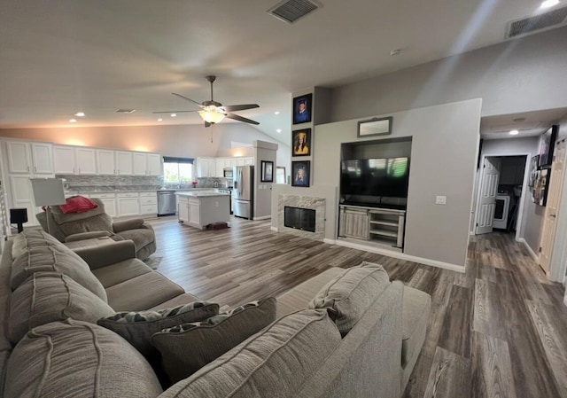 living room with a premium fireplace, ceiling fan, wood-type flooring, and vaulted ceiling