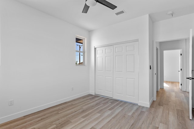 unfurnished bedroom featuring light wood finished floors, baseboards, visible vents, ceiling fan, and a closet