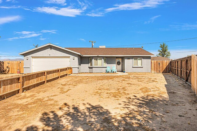 rear view of house with fence private yard, a garage, and stucco siding