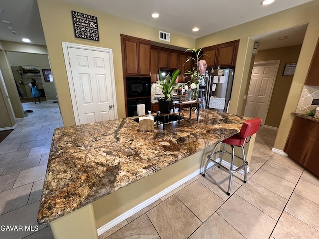2812 Crocus Pl, Palmdale, CA 93551 - kitchen featuring black appliances, dark stone countertops, a breakfast bar area, recessed lighting, and a spacious island