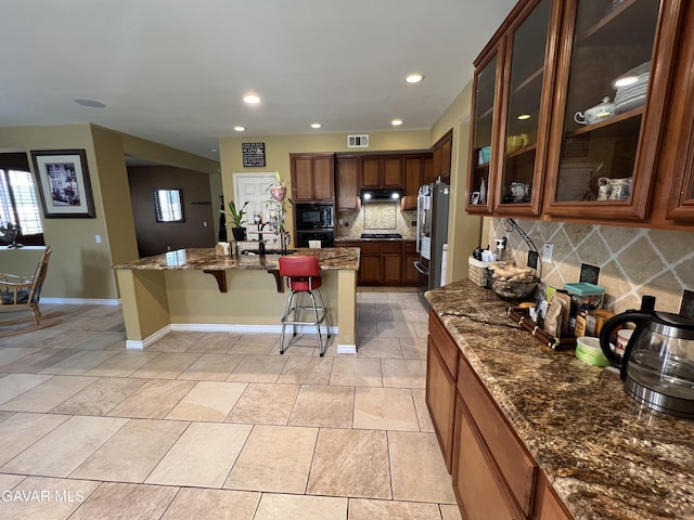 2812 Crocus Pl, Palmdale, CA 93551 - kitchen featuring a breakfast bar, appliances with stainless steel finishes, tasteful backsplash, under cabinet range hood, and dark stone countertops