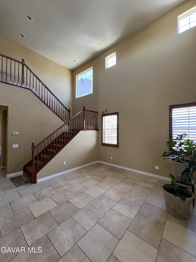 2812 Crocus Pl, Palmdale, CA 93551 - unfurnished living room with a high ceiling, stairway, plenty of natural light, and light tile patterned flooring