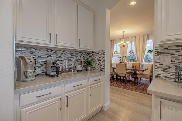 kitchen with white cabinets, a notable chandelier, and backsplash