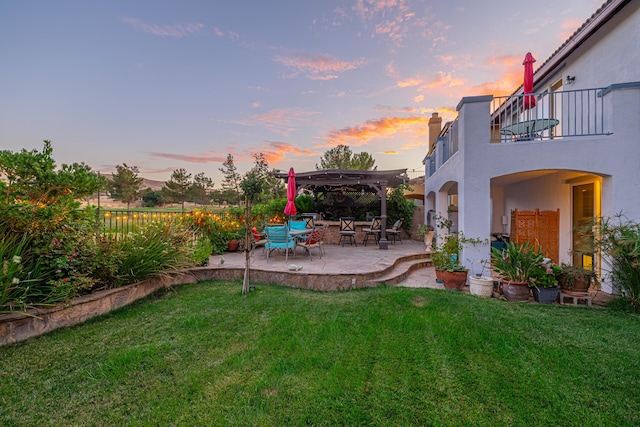 yard at dusk with a pergola, a patio area, and a balcony