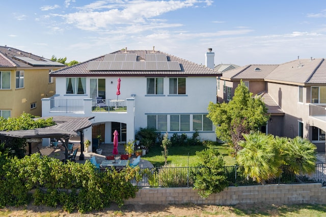 rear view of property with a patio area and solar panels