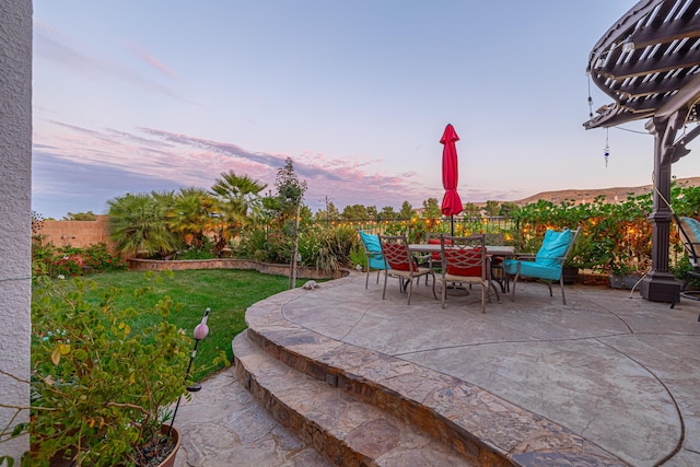 patio terrace at dusk featuring a lawn