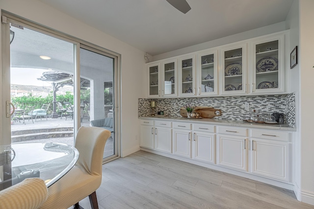 interior space featuring white cabinets, light stone countertops, backsplash, and light hardwood / wood-style flooring