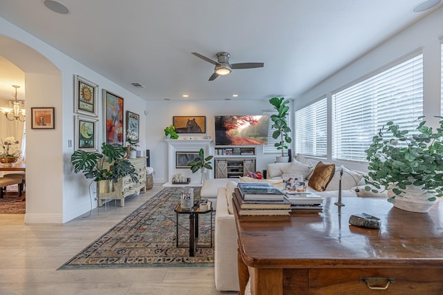 living room featuring ceiling fan with notable chandelier and light hardwood / wood-style floors