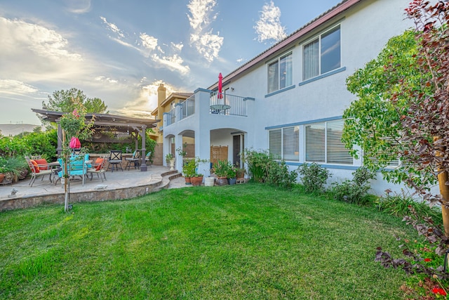 back of property with a lawn, a balcony, and a patio