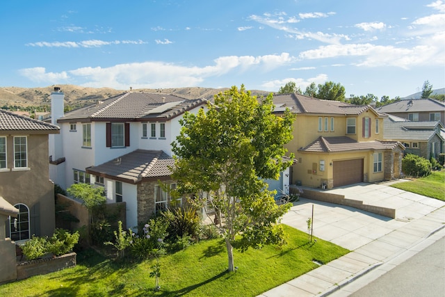 view of front of home featuring a mountain view, a front yard, and a garage